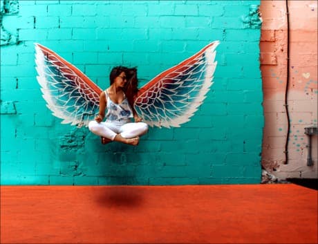 girl in front of an angel wing on a building