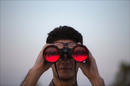 man looking through binoculars searching for happiness