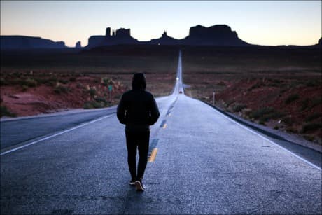a man walking down the road at sunset