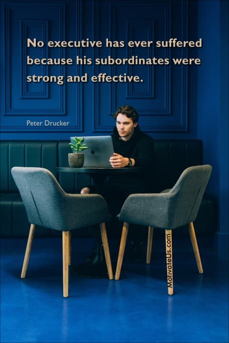 picture of a man sitting at a table with a laptop and a quote by Peter Drucker